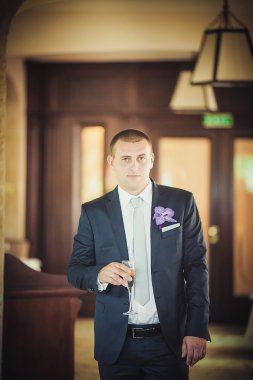 Mutlu yakışıklı gülümseyen damat yaka çiçeği ile siyah elbiseli