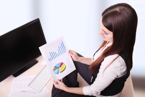 Young businesswoman sitting at table reading — Stock Photo, Image