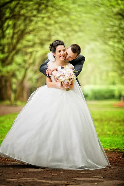 Couple en tenue de mariage avec un bouquet de fleurs et de verdure — Photo