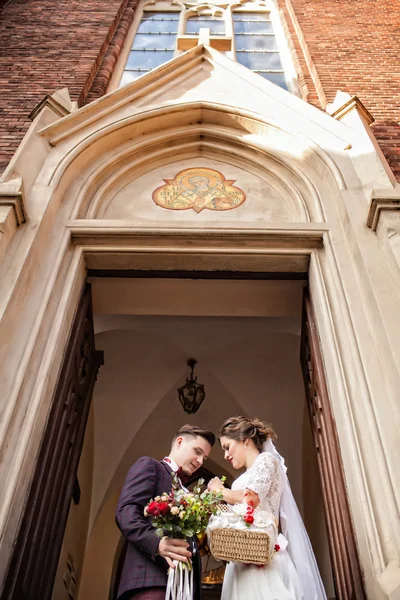 Svatební pár, nevěsta a ženich stojí proti kostelu — Stock fotografie