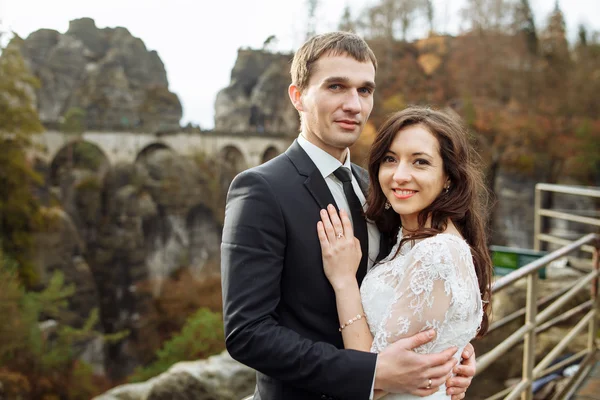 Couple de mariage debout dans les montagnes contre le ciel. Mignon moment romantique. Le meilleur jour de la vie de la mariée . — Photo