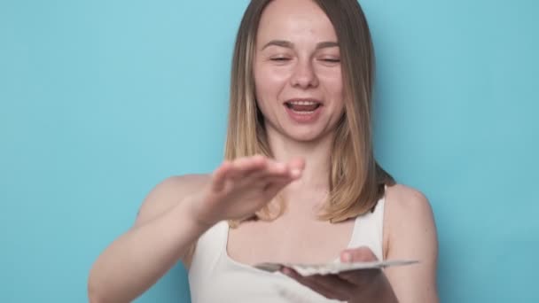 Szczęśliwa podekscytowana kobieta rzuca pieniądze na niebieskie tło — Wideo stockowe