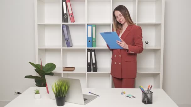 Leuke vrouw vult documenten in het kantoor — Stockvideo