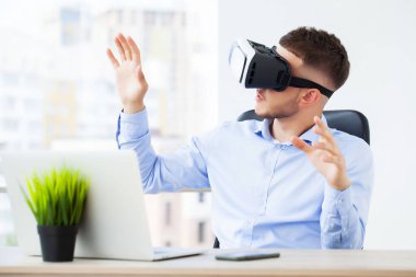 Modern ofiste sanal gerçeklik gözlüğü takan genç adam..