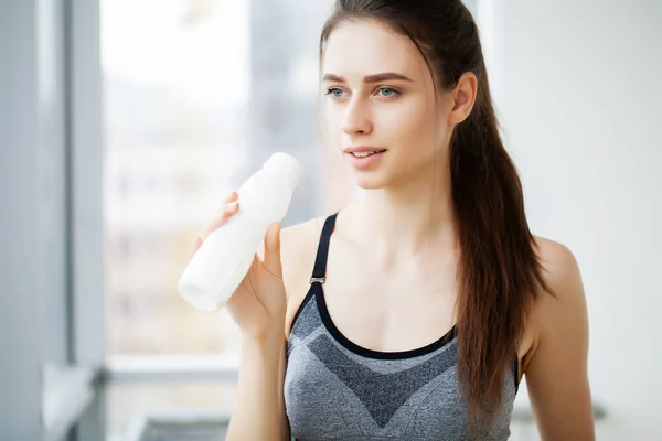 Молодая красивая женщина пьет из пластиковой бутылки йогурта — стоковое фото