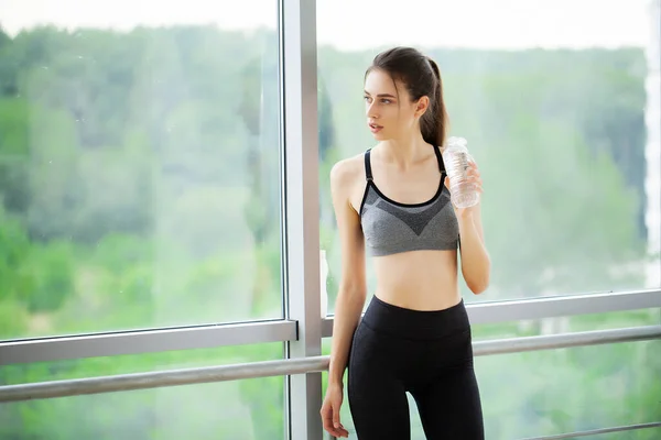 Mujer bebiendo agua en el gimnasio después de hacer ejercicio —  Fotos de Stock