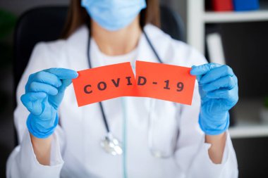 Octor elinde covid-19 yazılı kağıt bir kart tutuyor.