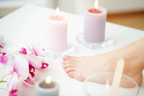 Beautician waxing female legs in spa center