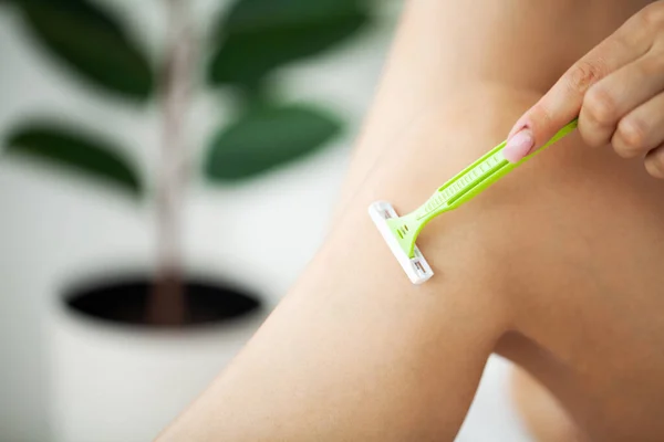 Skin care and health, fit woman shaving her legs with razor.