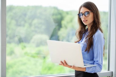 Ofiste dizüstü bilgisayarda çalışan genç bir kadın..