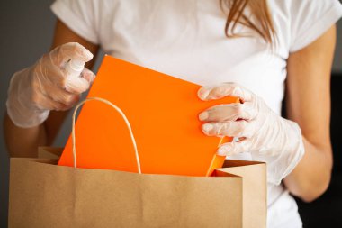 Koruyucu eldivenli bir kadının alışverişi dezenfekte etmesine yakın.