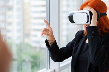 Modern çalışma stüdyosunda sanal gerçeklik gözlüğü takan genç bir kadın..