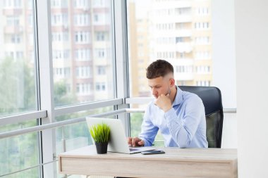 Ofisteki masasında oturan genç adamın portresi.