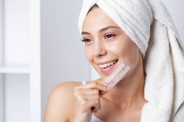 Beyaz dişleri olan, diş beyazlatmak için çizgili elleri olan güzel bir genç kız..