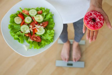 Kadın zararlı ve sağlıklı yiyecekler arasında seçim yapar.