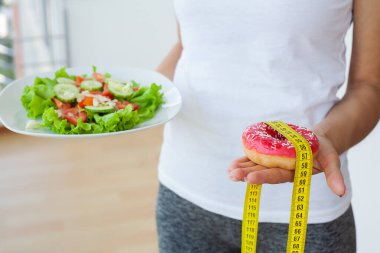 Kadın zararlı ve sağlıklı yiyecekler arasında seçim yapar.