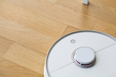 Akıllı Ev, elektrikli süpürge robotu oturma odasında ahşap zeminde koşuyor.