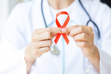 Doktor AIDS 'in sembolü olarak kırmızı kurdele tutuyor..