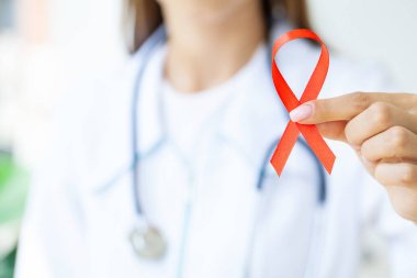 Doktor AIDS 'in sembolü olarak kırmızı kurdele tutuyor..
