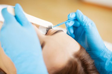 Kirpik uzatma ustası güzel bir kadına kirpiklerini uzatır.