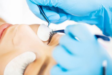 Kirpik uzatma ustası güzel bir kadına kirpiklerini uzatır.