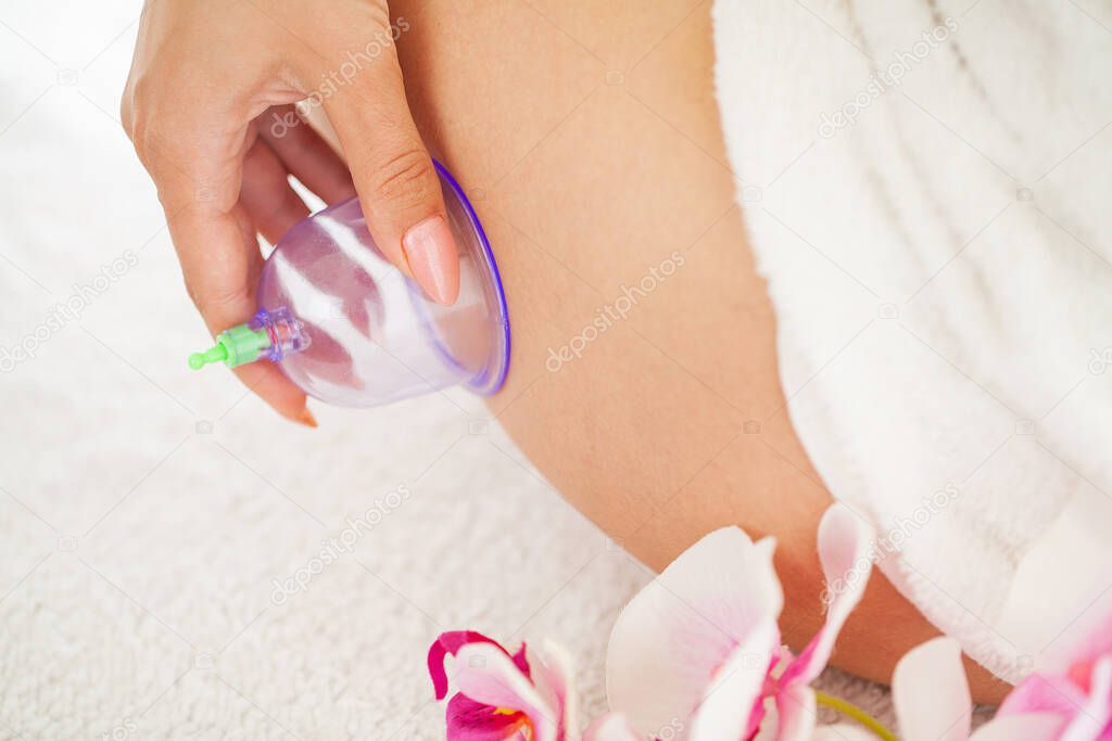 Woman getting anti-cellulite massage of hips with use of vacuum cans