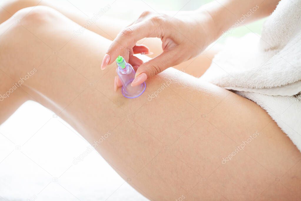 Woman getting anti-cellulite massage of hips with use of vacuum cans