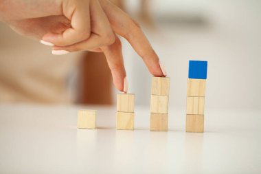 Kadın eli boş tahta küpleri girdi ifadeleri ve bilgi simgesi için kopyalama alanı ile birlikte masaya yerleştiriyor ve istifliyor.