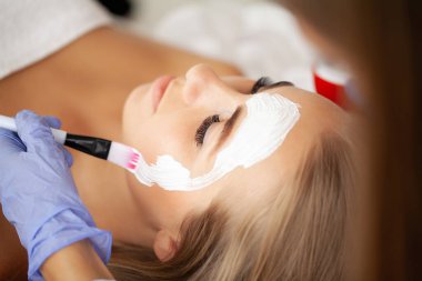 Yüzünde kil maske olan çekici ve komik bir kadın..