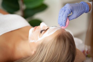 Güzellik stüdyosunda kaplıca maskesi takan bir kadın..