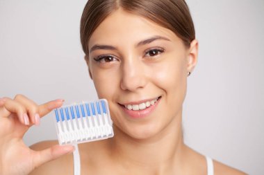 Kadın dişleri temizlemek için fırça kullanıyor.