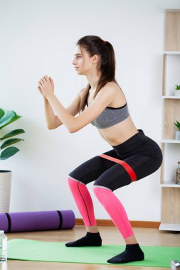 Güzel genç bir kadın evde spor yapıyor.