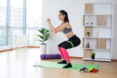 Güzel genç bir kadın evde spor yapıyor.