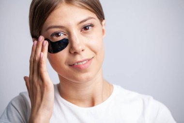 Güzel ciltli genç bir kadın yüzüne siyah lekeler koyar.