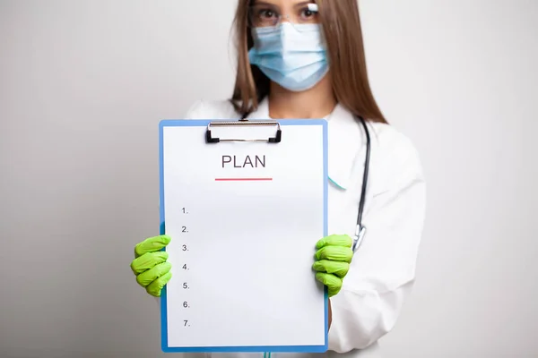 Woman doctor in white coat holds a letter with a plan of action