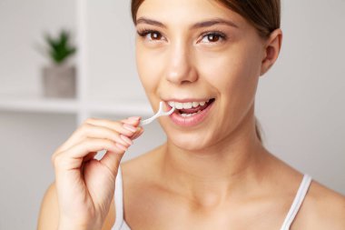 Banyoda diş ipi kullanan neşeli esmer kadın.