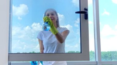 Pencereleri süngerle temizleyen genç bir kadın.