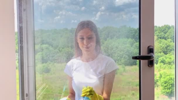 Mladá usměvavá žena mytí oken s houbou — Stock video