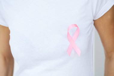 Göğüs kanserini sembolize eden pembe kurdele gösteren bir kadın.