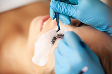 Kirpik uzatma işlemi, profesyonel bir stilist kadınların kirpiklerini uzatır.