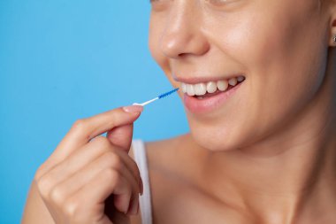 Kadın interdental alanları temizlemek için fırça kullanır
