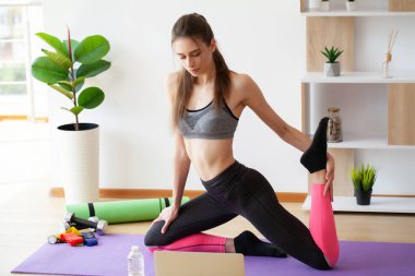 Evde yoga ve esneme hareketleri yapan çekici bir kadın.