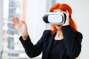 Modern çalışma stüdyosunda sanal gerçeklik gözlüğü takan genç bir kadın..