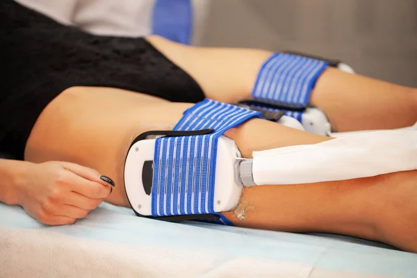 Patient applying electrical stimulation therapy on legs.