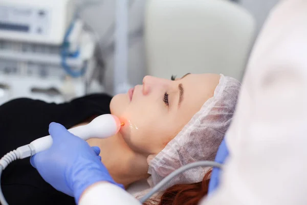 Patient applying electrical stimulation therapy on face.