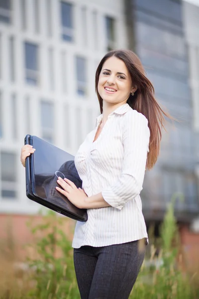 Happy business woman holding laptop and smiling — Stock Photo, Image