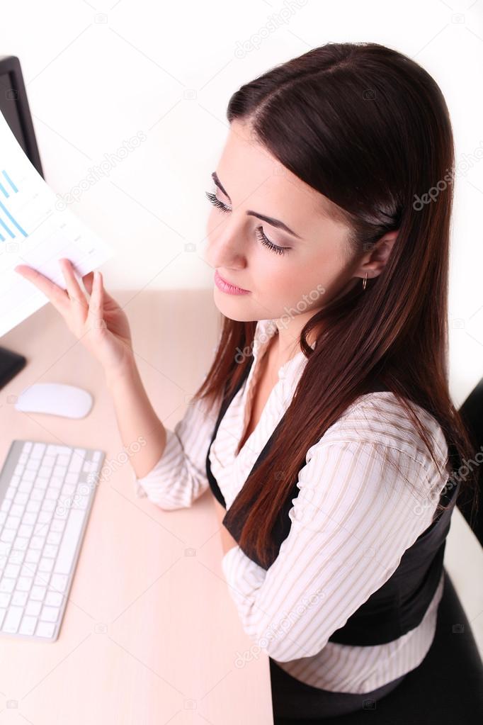 Beautiful business woman looking at papers she holding in her ar