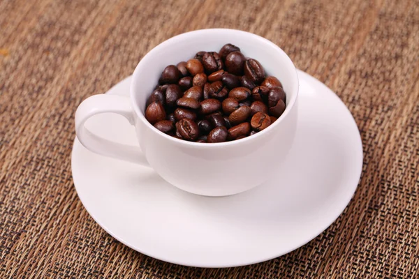 Taza de café con granos de café frescos sobre un fondo marrón — Foto de Stock