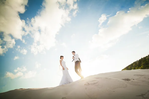 Kärlek brudparet körs på sanden. Bruden och brudgummen — Stockfoto