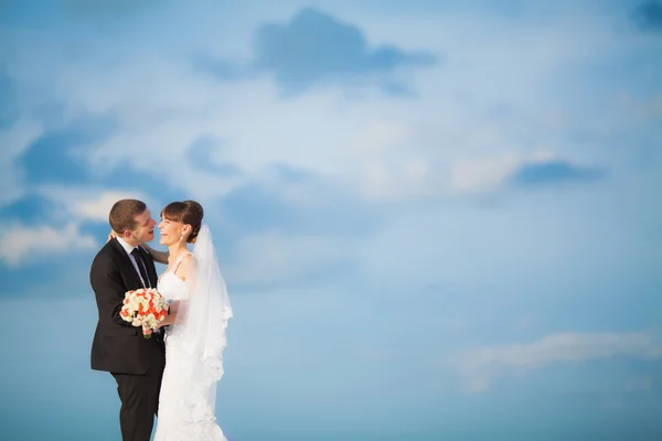 Sensuella bruden och brudgummen på moln bakgrund — Stockfoto